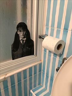 a bathroom with blue and white stripes on the walls, toilet paper roll in front of it