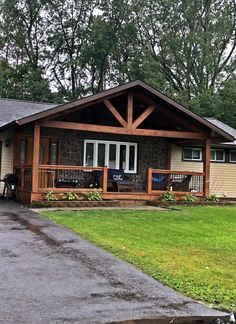 a house that is sitting in the grass with a porch and covered patio area next to it