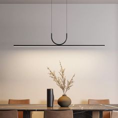 a dining room table with chairs and a vase on it's centerpiece in front of a white wall