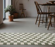 a checkered rug sits on the floor in front of chairs and table with potted plants