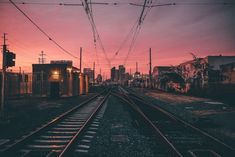 the train tracks are empty as the sun sets in the cityscape behind them