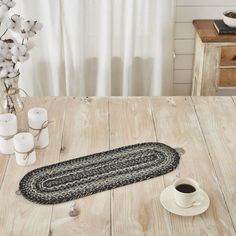 a table with a coffee cup, candle and rug on it