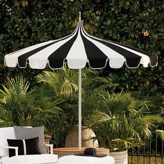 a black and white striped umbrella sitting on top of a table next to a chair