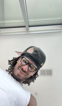 a man with glasses and a hat is posing for a photo in front of a mirror