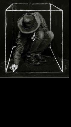 a black and white photo of a man kneeling down in front of a glass box