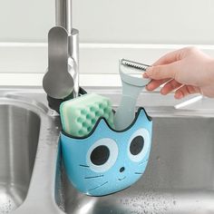 a toothbrush holder in the shape of a cat is being held by a person's hand