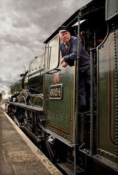 a man standing on the side of a green train