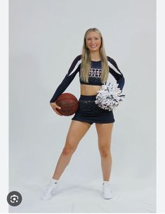 a cheerleader holding a basketball and pom - poms posing for a photo