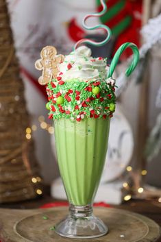 a green drink topped with whipped cream and sprinkles on top of a table