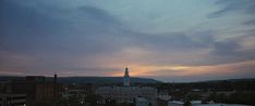 the sky is very dark and cloudy at dusk, with buildings in the foreground