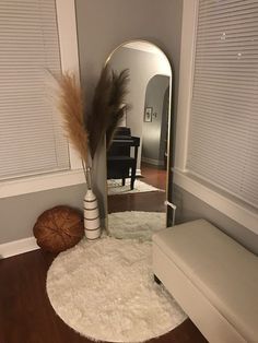 a mirror sitting on top of a wooden floor next to a white bench and ottoman