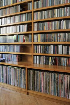 a large wooden book shelf filled with lots of dvd's on top of hard wood floors