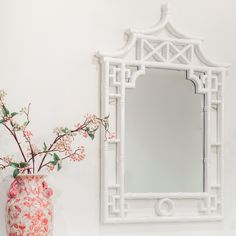 a vase with flowers in it next to a mirror