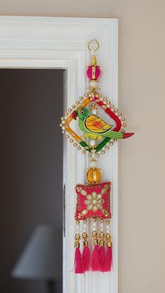 a colorful bird hanging from the side of a door with beads and tassels