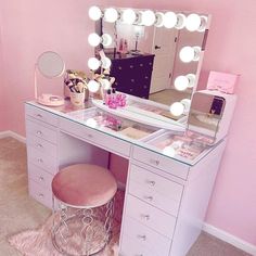 a vanity with lights, stool and mirror in a pink walled room on top of carpeted floor