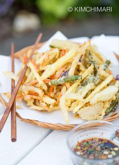 a white plate topped with lots of food next to chopsticks and seasoning