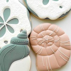 three decorated cookies sitting next to each other on top of a white tablecloth with blue and pink decorations