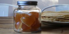 a glass jar filled with jelly hearts next to a plate of pancakes