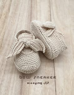 a pair of crocheted baby shoes sitting on top of a wooden floor with the words bow knitted