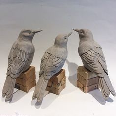 three birds sitting on top of wooden blocks