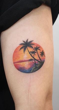 a woman's thigh with a sunset and palm trees tattoo