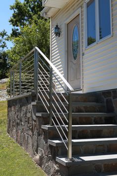 a house with stone steps leading up to the front door and side entrance, on a sunny day