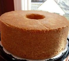 a round cake sitting on top of a black plate next to a window sill