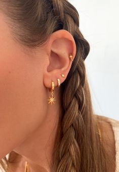 a close up of a person wearing gold earring with stars on the back of their ears