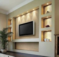 a tv mounted on the wall above a fireplace in a living room with built - in shelves