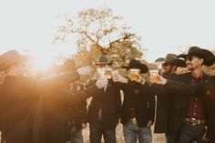 a group of men standing next to each other holding up beer glasses in front of them