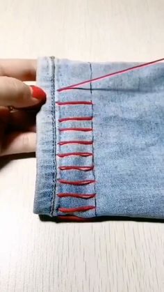 a woman's hand holding onto a piece of denim