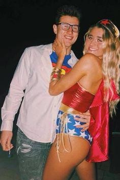 a man standing next to a woman wearing a superman costume on top of her chest