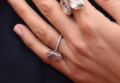 a woman's hand with two rings on it and an engagement ring in the middle