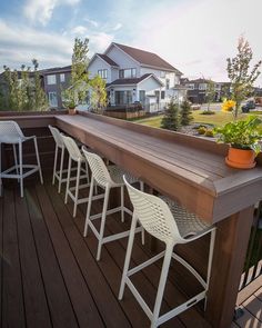 there are four chairs that are on the deck and one is sitting at the bar