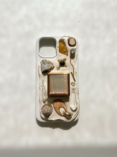 a cell phone case with various items in it on a white surface, including rocks and stones