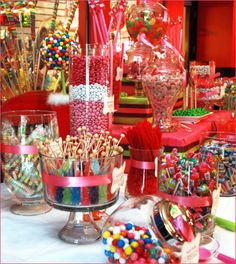 a table topped with lots of candy canes and lollipops in vases