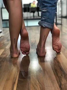 two people standing on top of a wooden floor with their bare feet in the air