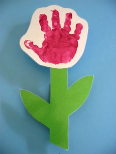 a paper flower with handprints on it sitting next to a blue background,