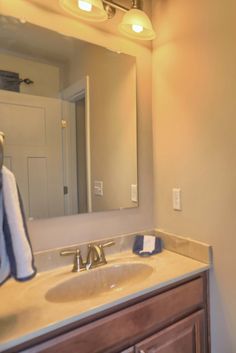 a bathroom with a sink, mirror and towel hanging on the rack in front of it