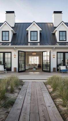 a white house with lots of windows and wooden walkway leading up to the front door