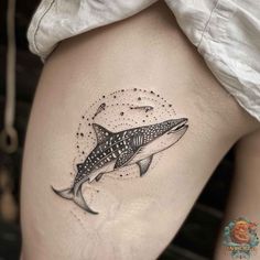 a tattoo on the thigh of a woman's leg with a whale and stars