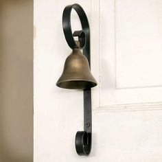 a bell mounted to the side of a white door next to a black metal hook