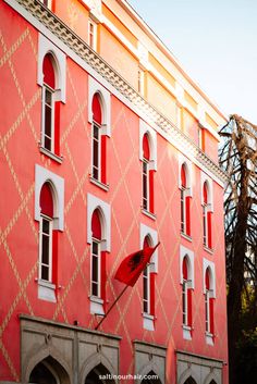 an orange and white building with red shutters on the front, and a red umbrella sticking out of it's window