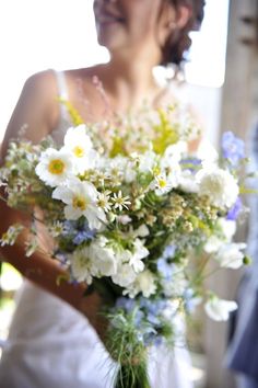 a bride holding a bouquet of white and blue flowers