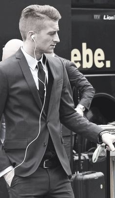 a man in a suit and headphones standing next to a bus