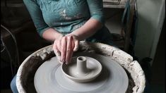 a woman is making a pottery pot on a potter's wheel with her hands