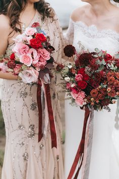 two brides holding bouquets with red and pink flowers