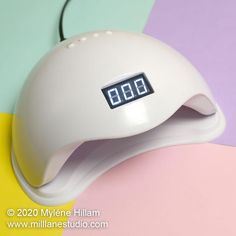 a white alarm clock sitting on top of a colorful table next to a yellow and pink wall