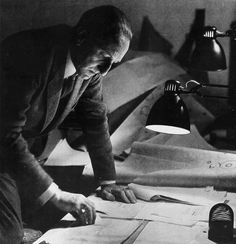 a man sitting at a desk in front of a lamp and papers on the table