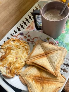 toast and eggs are on a plate next to a cup of coffee